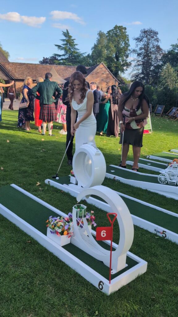 Bride playing the wedding crazy golf course on the lawn at Barns & Yard, Worcestershire