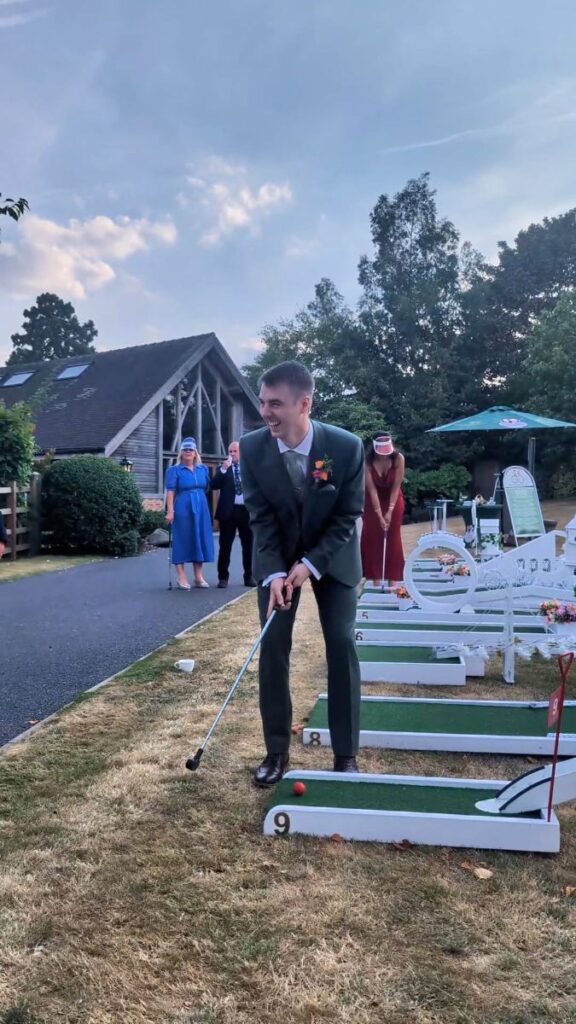 Groom lining up a putt on the wedding crazy golf course at Mythe Barn