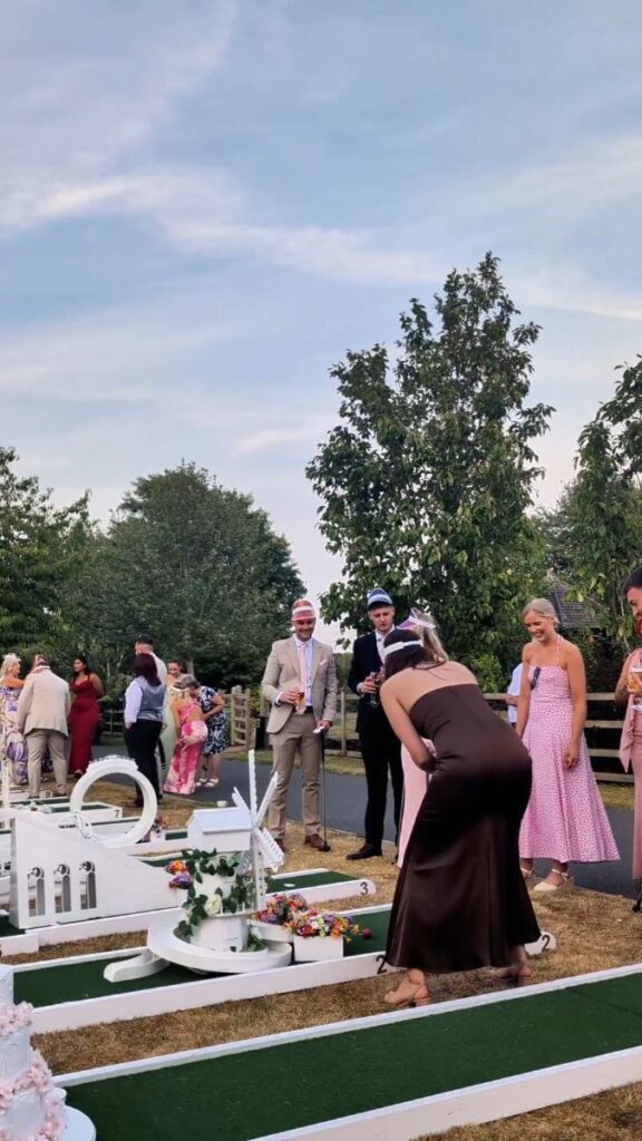 A wedding guest playing crazy golf on the lawn at Mythe Barn