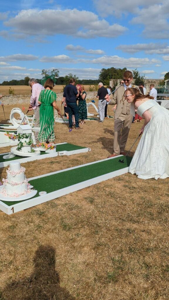 Bride lining up a putt on the wedding crazy golf course at Normanton Park Gardens