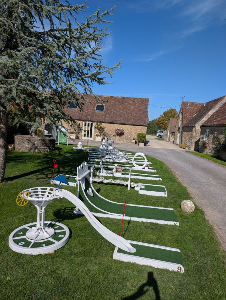 The Crazy Weds wedding crazy golf course on the lawn at Stratton Court Barn, with the stone barns behind