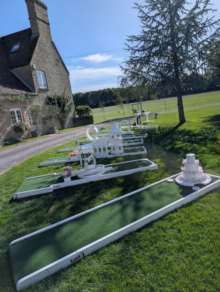 Crazy golf holes on the lawn at Stratton Court Barn with the stone farmhouse behind