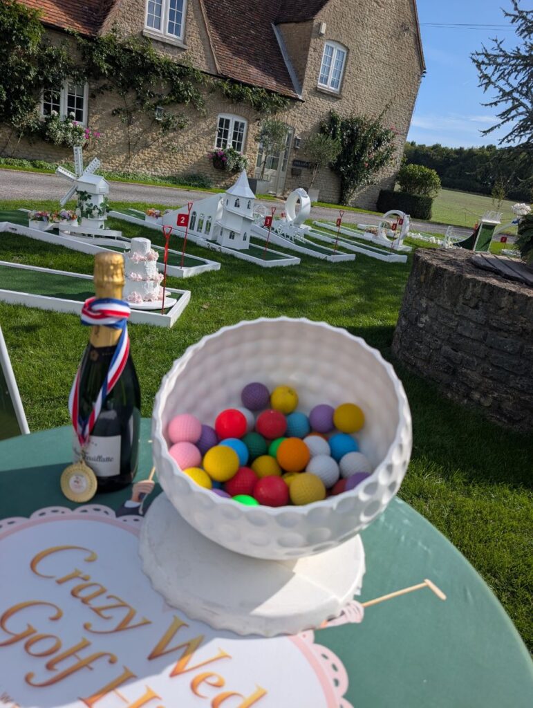 The Crazy Weds welcome table with golf balls and a prize bottle at Stratton Court Barn